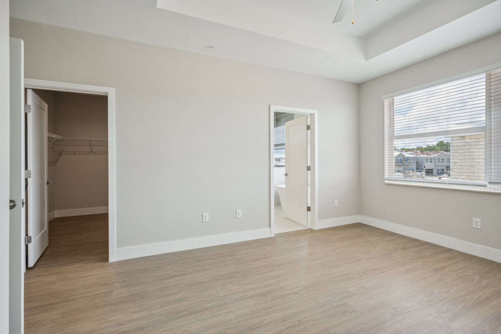 the living room of an apartment with a large window and wooden floors